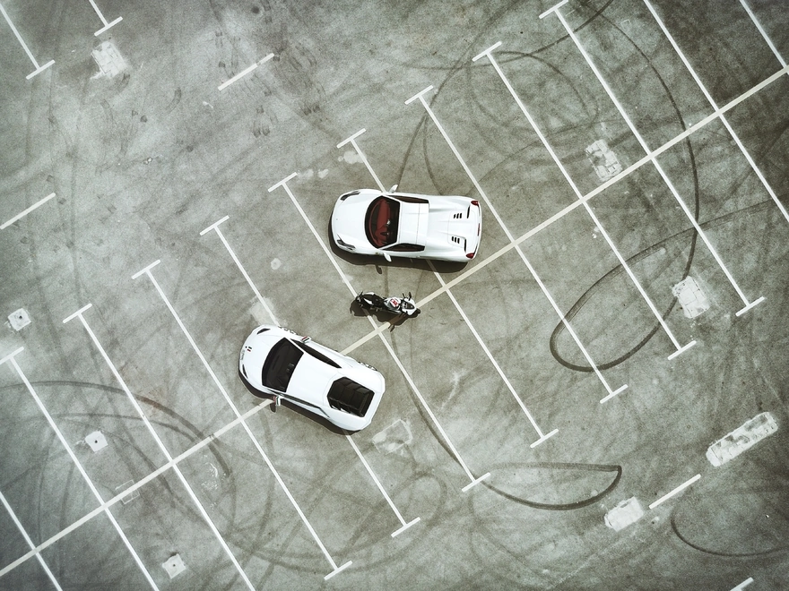 Две белые машины и мотоцикл на парковке