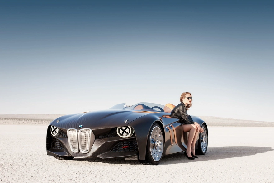 Стильная девушка сидит на стильном автомобиле в пустыне
