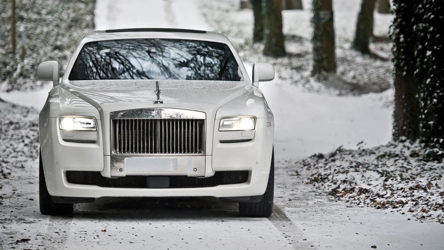 Машина бизнес класса Rolls-Royce Ghost Series II зимой со включёнными фарами