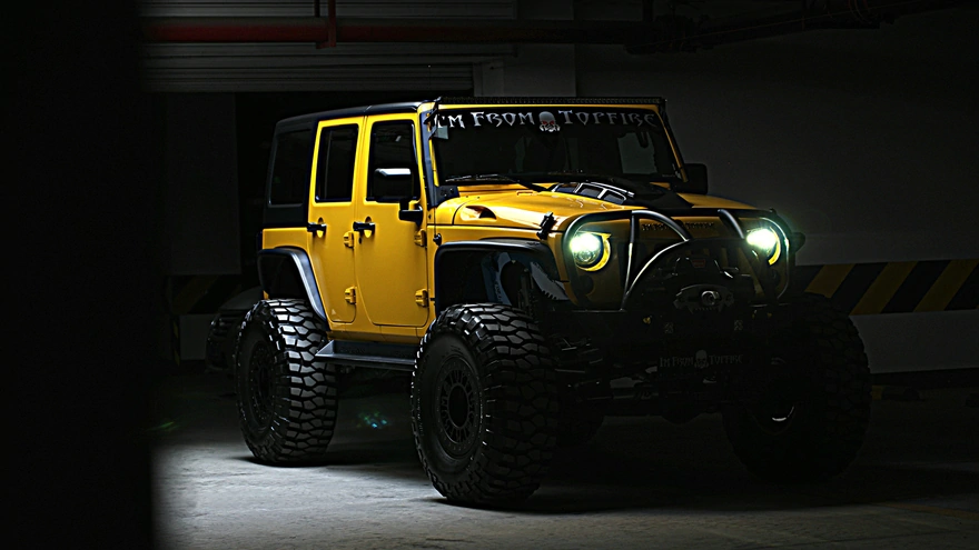 Yellow Jeep Wrangler shines headlights