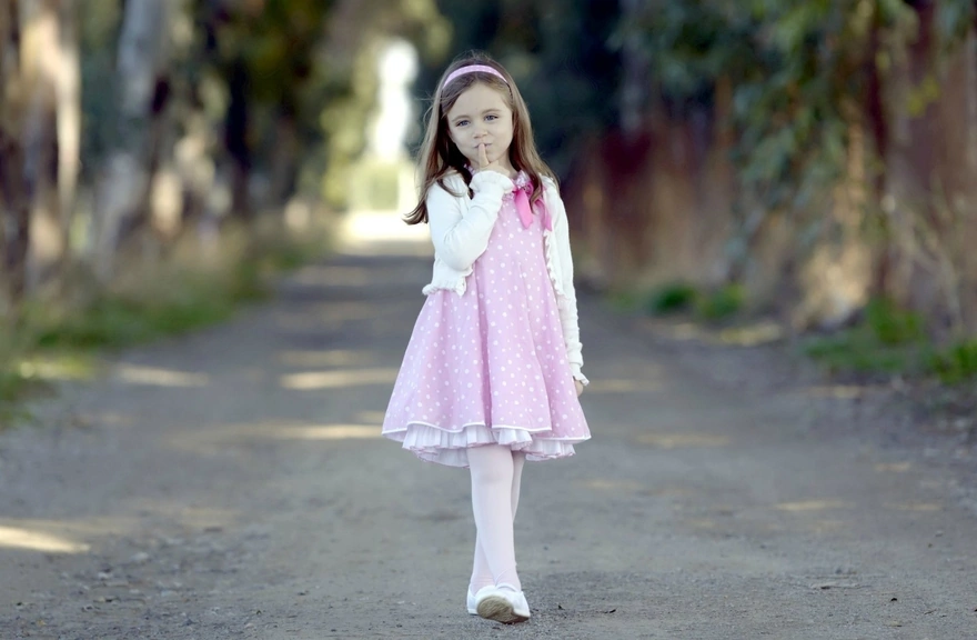 Девочка в розовом платье гуляет по парку
