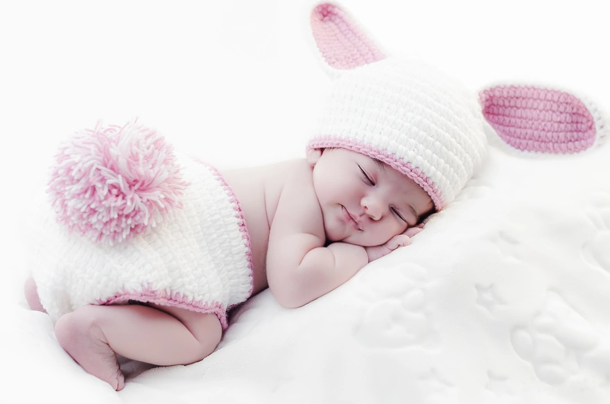 Младенец в вязаном костюмчике кролика