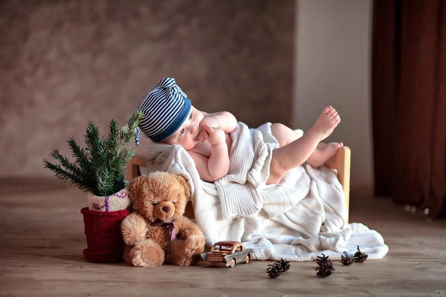Малыш в шапочке лежит среди игрушек