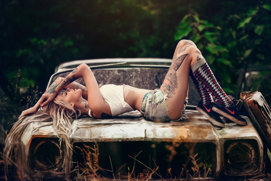 Girl posing lying on a rusty old car