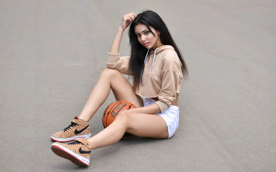 Красивая брюнетка сидит с баскетбольным мячом