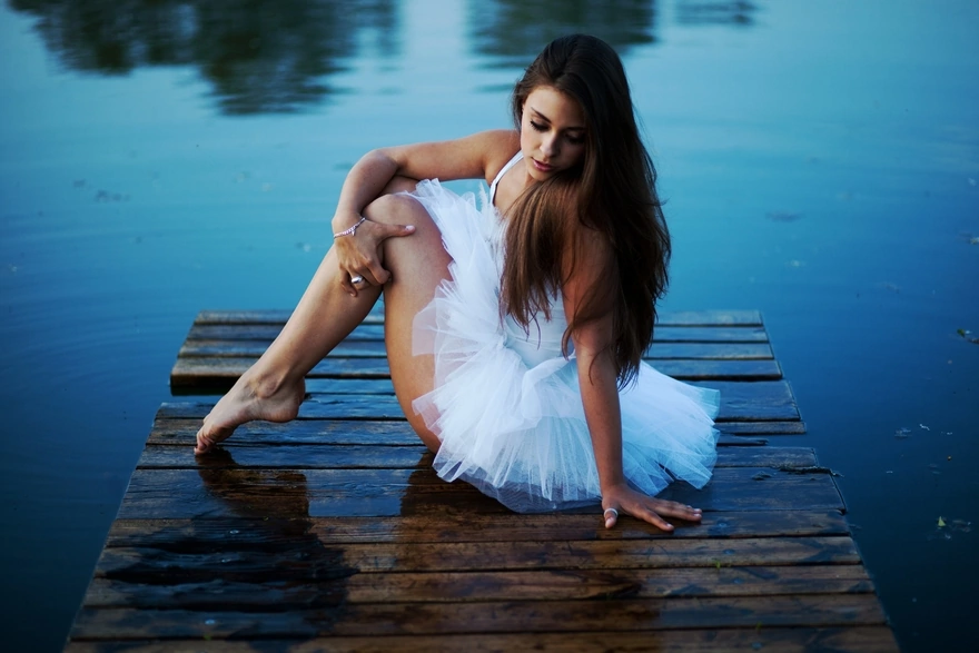 Girl in white tutu sitting on the dock