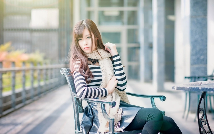 Азиатка в шарфе сидит на стуле