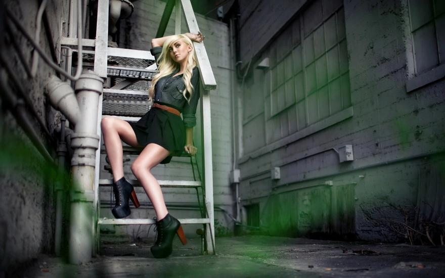 Блондинка в ботинках с высоким каблуком позирует на лестнице