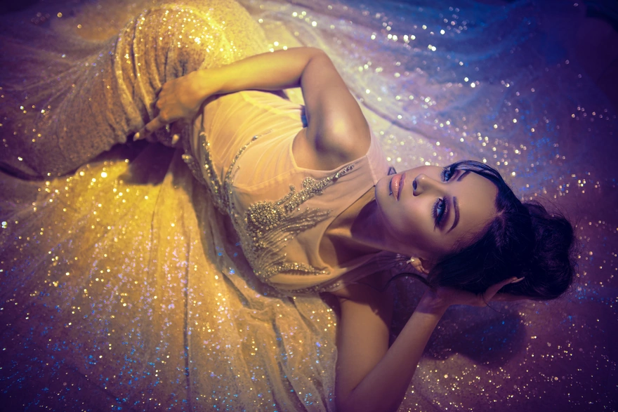 Beautiful brunette lying down posing in dress with sequins