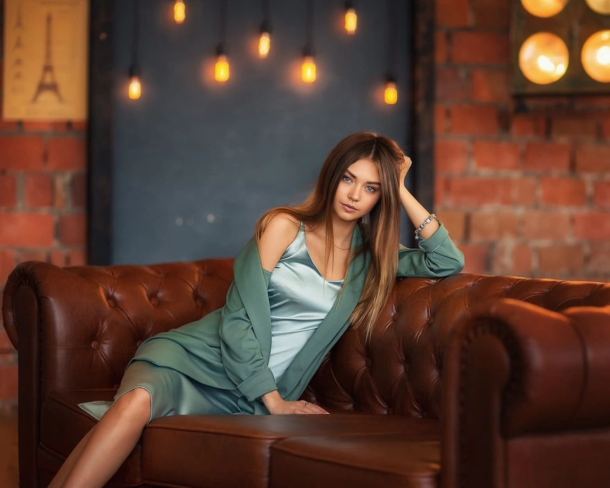 Модель Полина Костюк сидит на кожаном диване