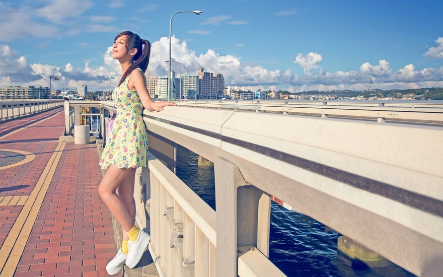 A girl stands on a bridge with a beautiful view of the city