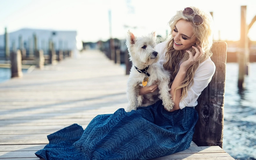 Девушка с собакой сидят на пирсе