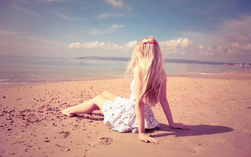 Девушка в красивом платье сидит на берегу моря