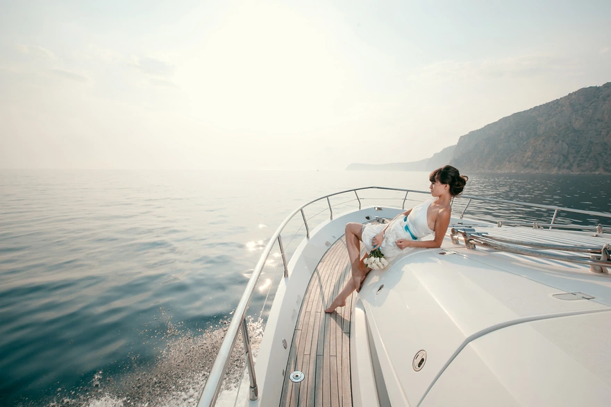 Девушка с цветами на яхте смотрит на горизонт в море