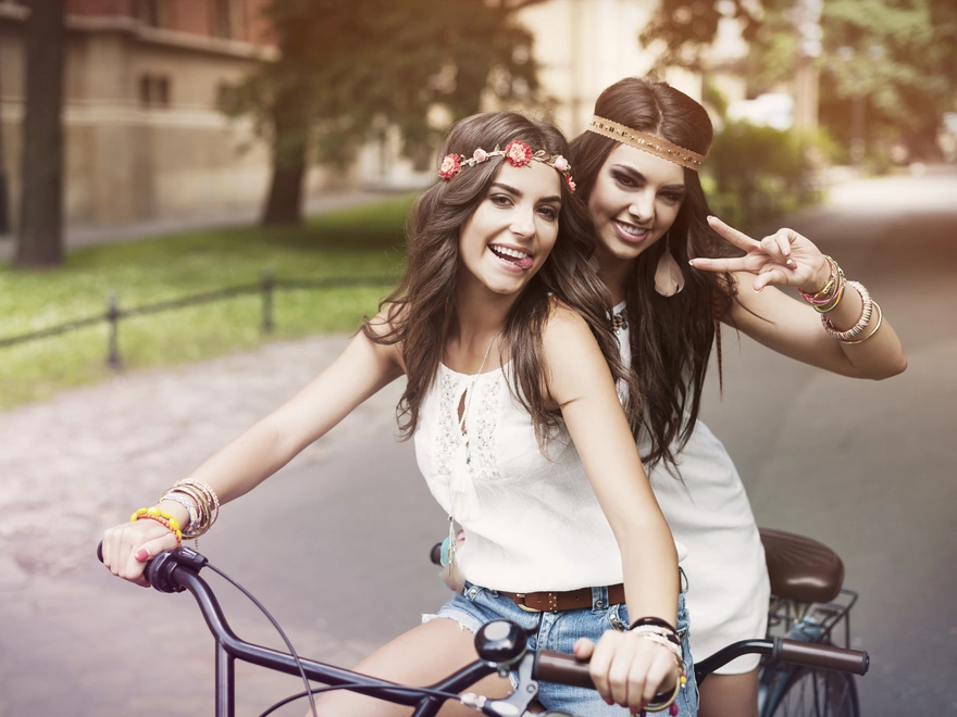 Две девушки на велосипеде позируют фотографу