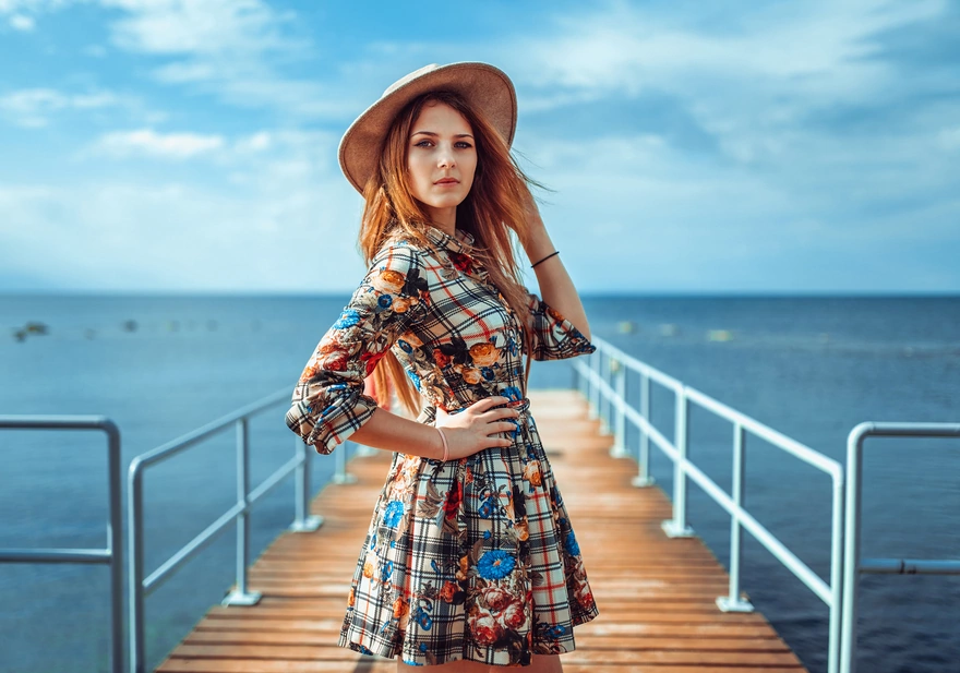 Image: Girl, blonde hair, hat, dress, pier, water, sky, clouds