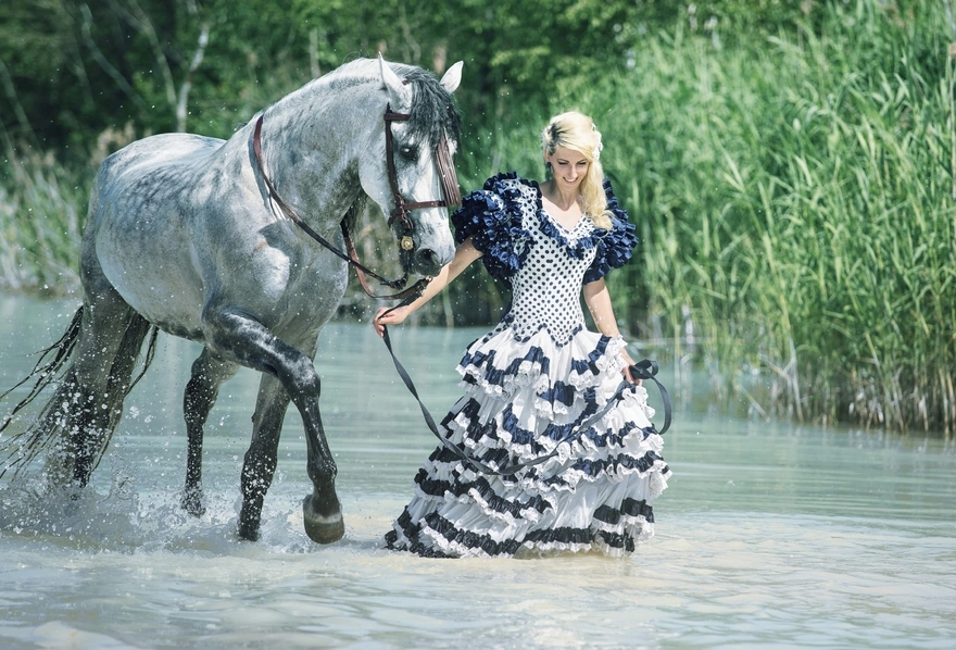 Девушка гуляет с лошадью по речной воде