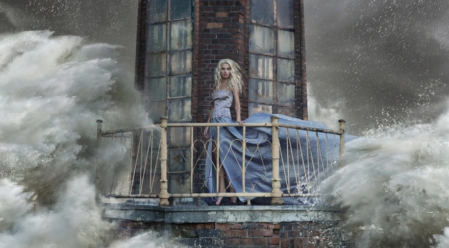Девушка в голубом платье стоит на балконе маяка