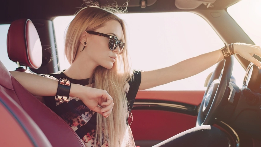 Девушка в солнцезащитных очках сидит за рулем авто
