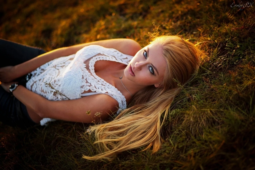 Girl in white lying on the grass with a passionate glance