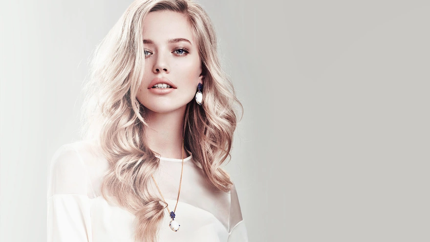 Blonde in white dress and jewelry on a light background