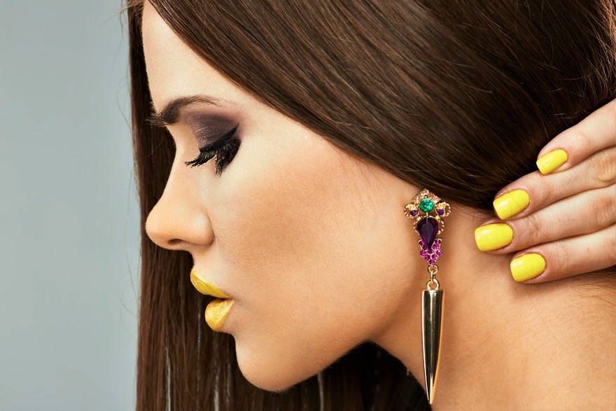 Girl with bright makeup and manicure shows massive earrings