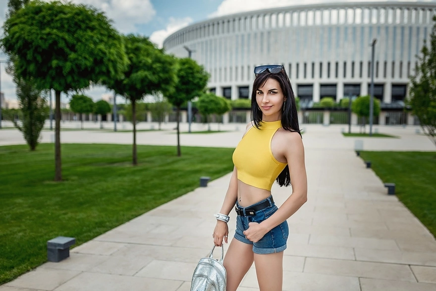 Lioka Grechanova in yellow top and shorts posing on the background of the building