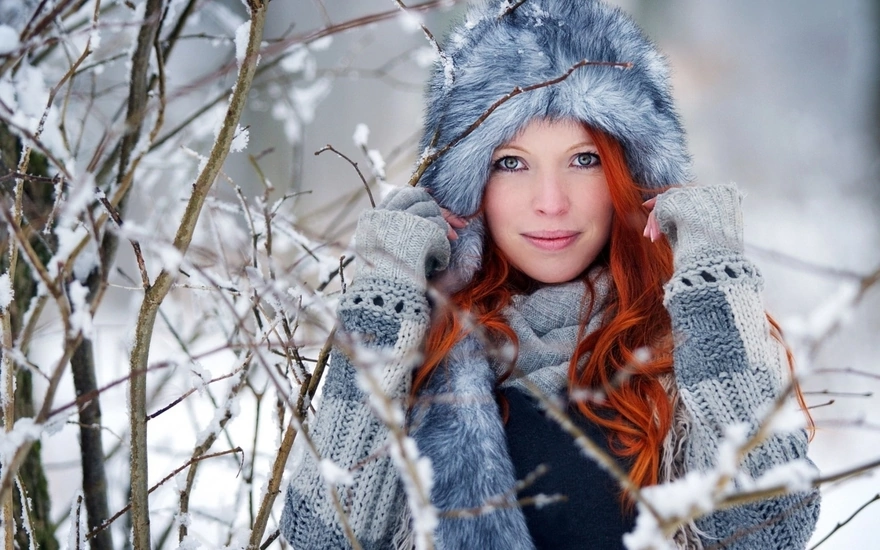 Девушка в меховой шапке, возле веток зимой