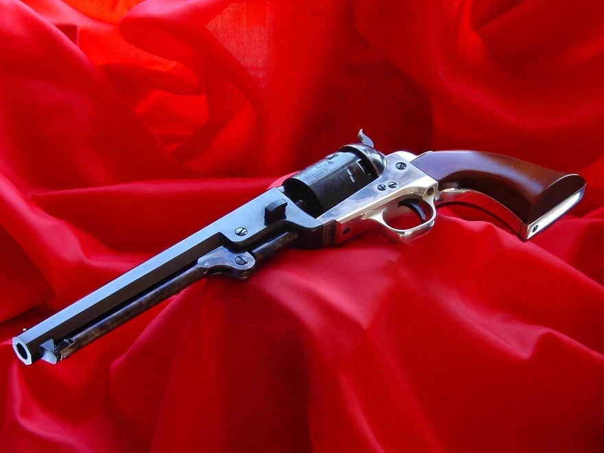 Револьвер лежит на фоне красной ткани