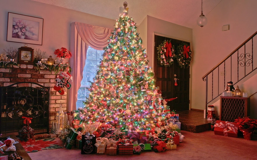 Красивая и нарядная Рождественская ёлка с подарками стоит в доме у камина