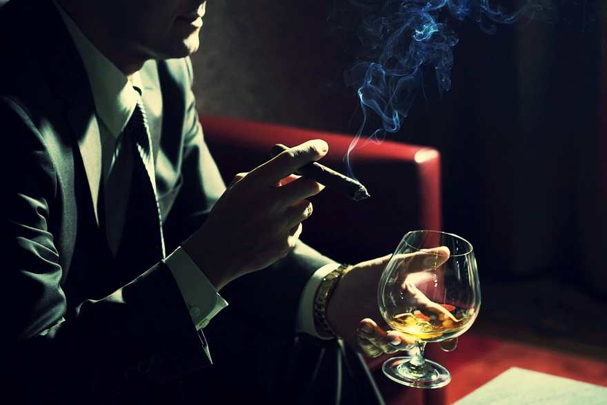 Деловой мужчина держит сигару и бокал спиртного