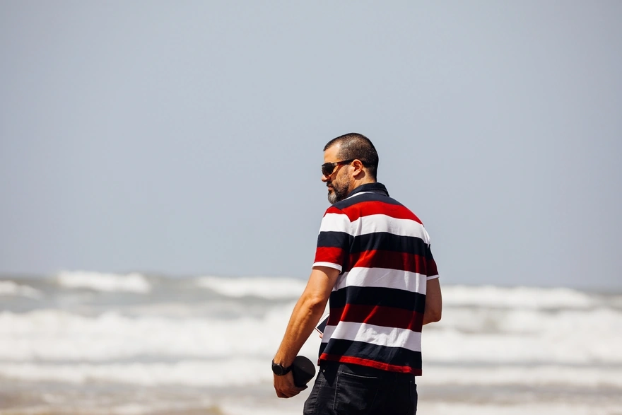 Мужчина в полосатой футболке на берегу океана
