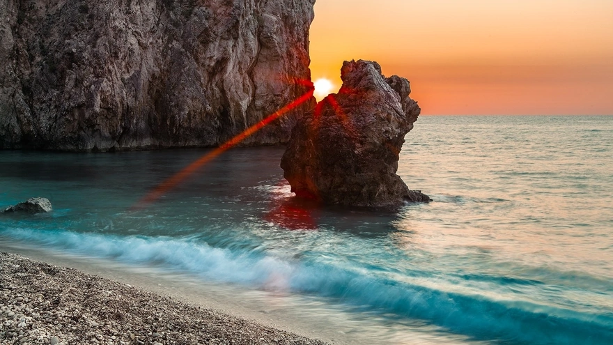 Солнце садится за скалами, с видом на море