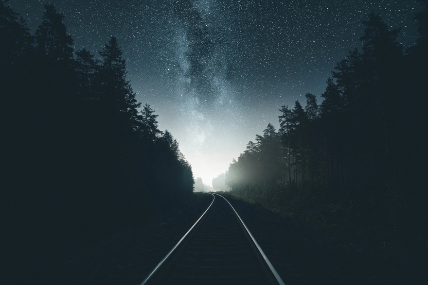 Railroad in the woods under the stars of the night milky way