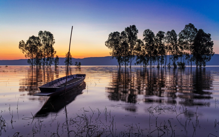 Лодка на озерной глади на закате дня