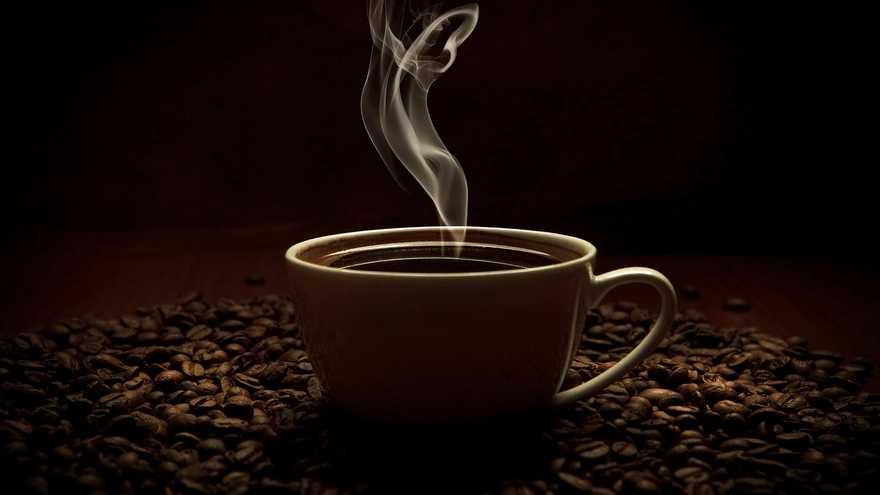 Чашечка ароматного напитка стоит в зёрнах кофе