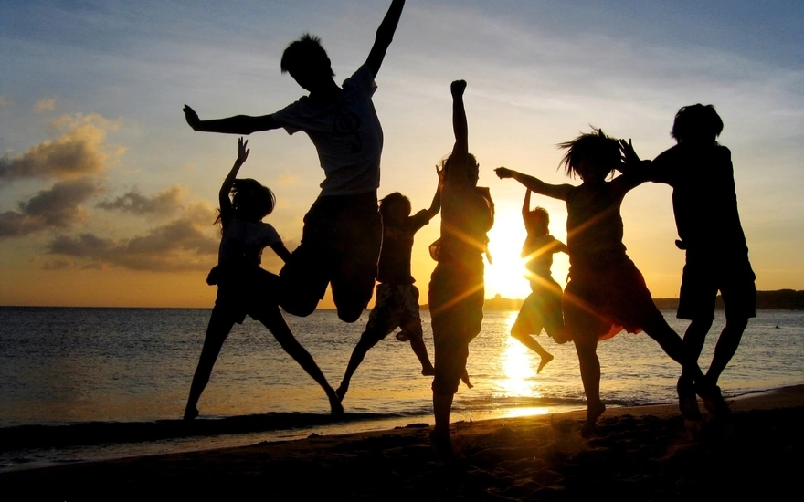 Компания друзей веселятся на берегу моря при закате