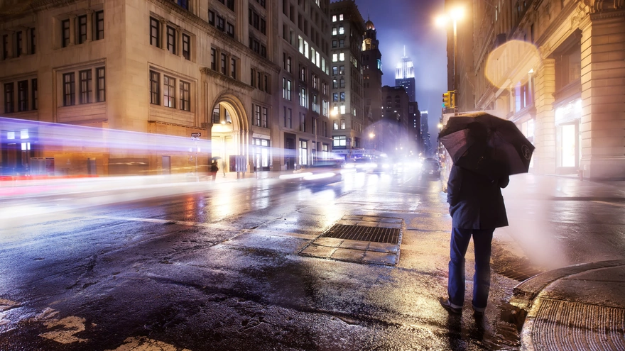 Мужчина под зонтом идёт по улице