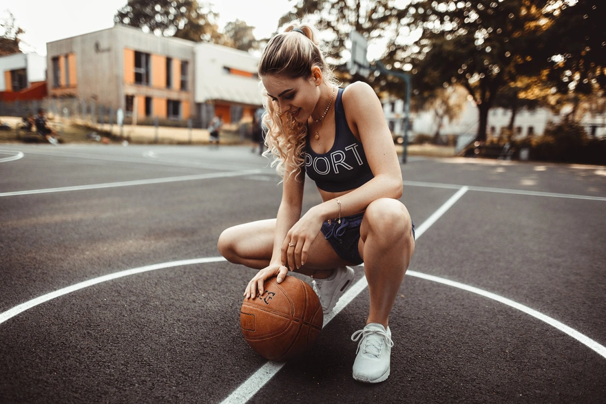 Девушка позирует с баскетбольным мячом на корте
