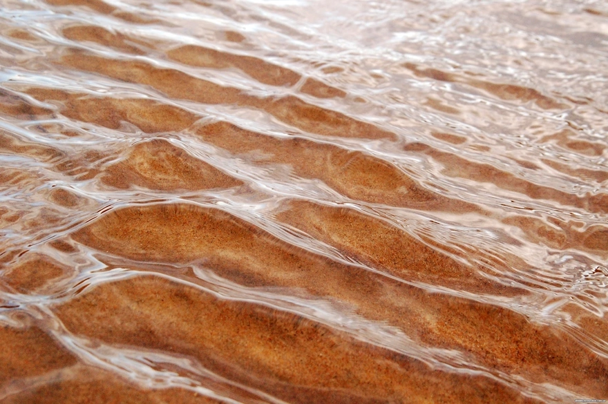 Рябь воды на фоне песка