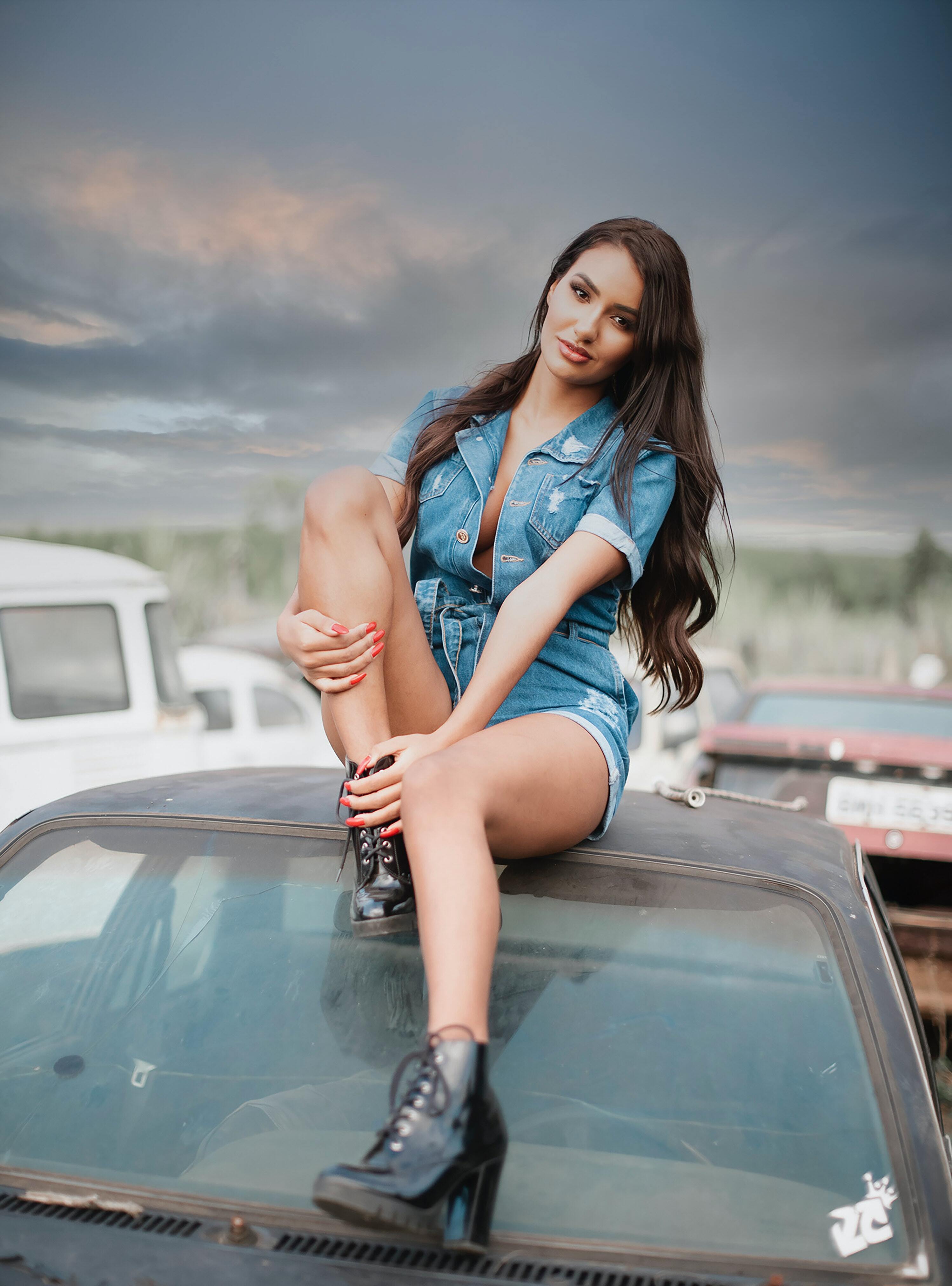 Image: Brunette, smile, legs, boots, hair, sitting, car, roof, sky, weather