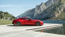 Картинка: Красный автомобиль Aston Martin на фоне озера и гор.
