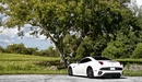 Картинка: Белая Ferrari California стоит у дерева.