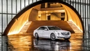 Картинка: Белый Cadillac CT6 стоит при необычном входе в здание с освещением