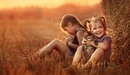 Картинка: Две девочки в поле у стога сена гладят и обнимают котят.