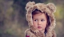 Картинка: Девочка в жилетке с ушками медведя смотрит в сторону.