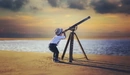 Image: Little boy looking through a telescope at the sky