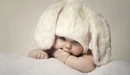 Картинка: Малыш в белой шапочке с ушками зайчика.