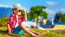 Картинка: Мальчик в шляпе и очках сидя на траве смотрит вдаль