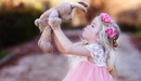 Картинка: Девочка тянется губами к игрушечному зайчику.